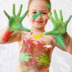 Child with Green Hands and Paint Splatters on White Background
