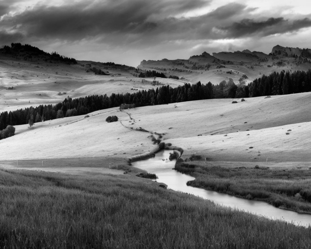 Tranquil black and white landscape with winding river and rolling hills