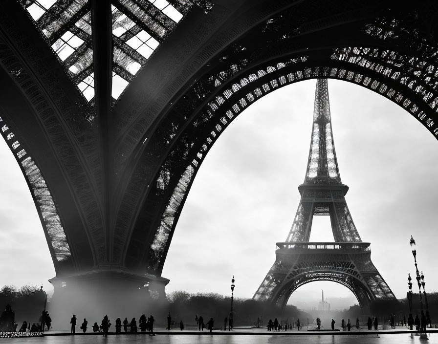 Monochromatic Eiffel Tower silhouette with visitors in misty backdrop