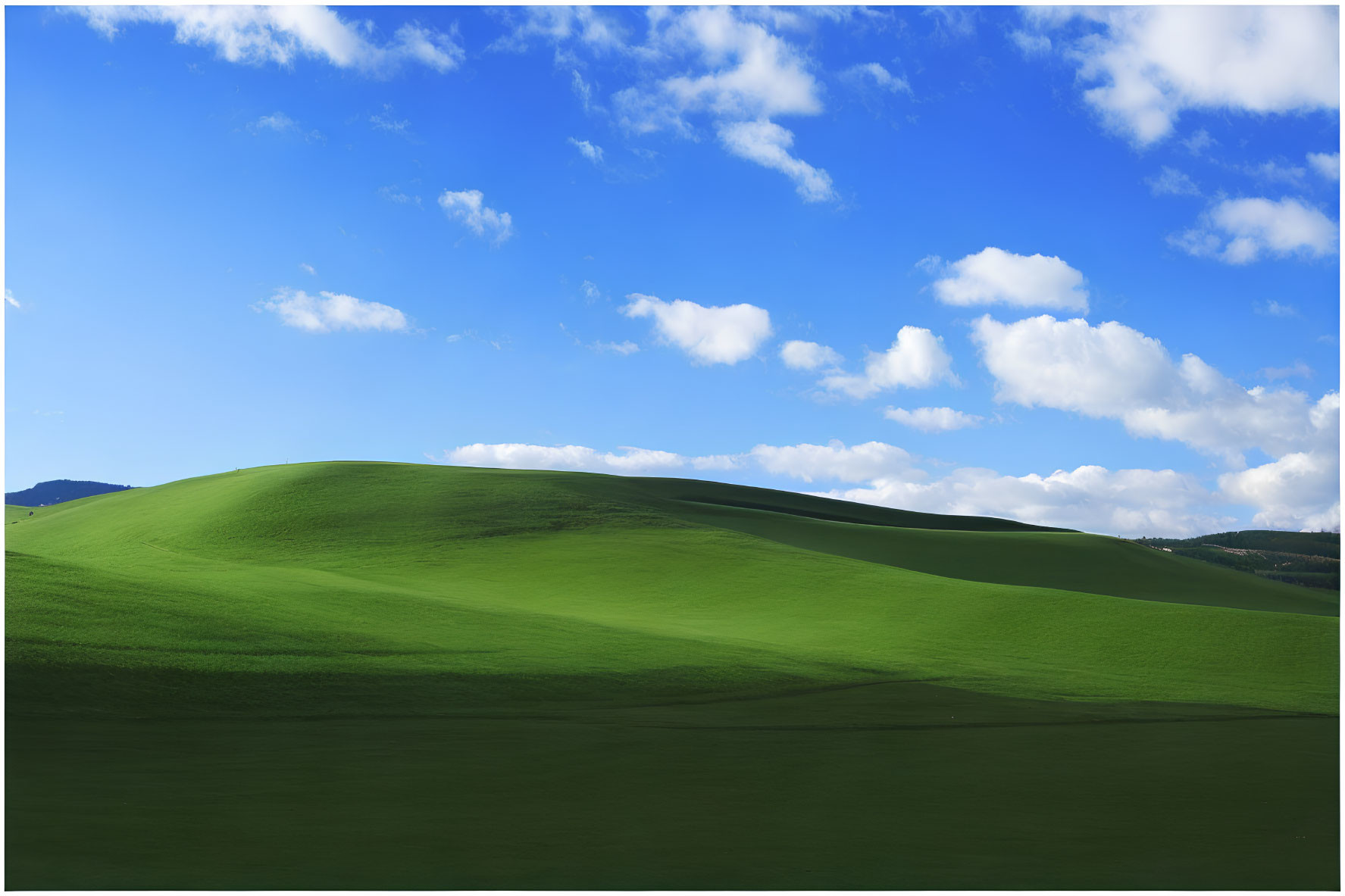 Scenic view of rolling green hills under vibrant blue sky