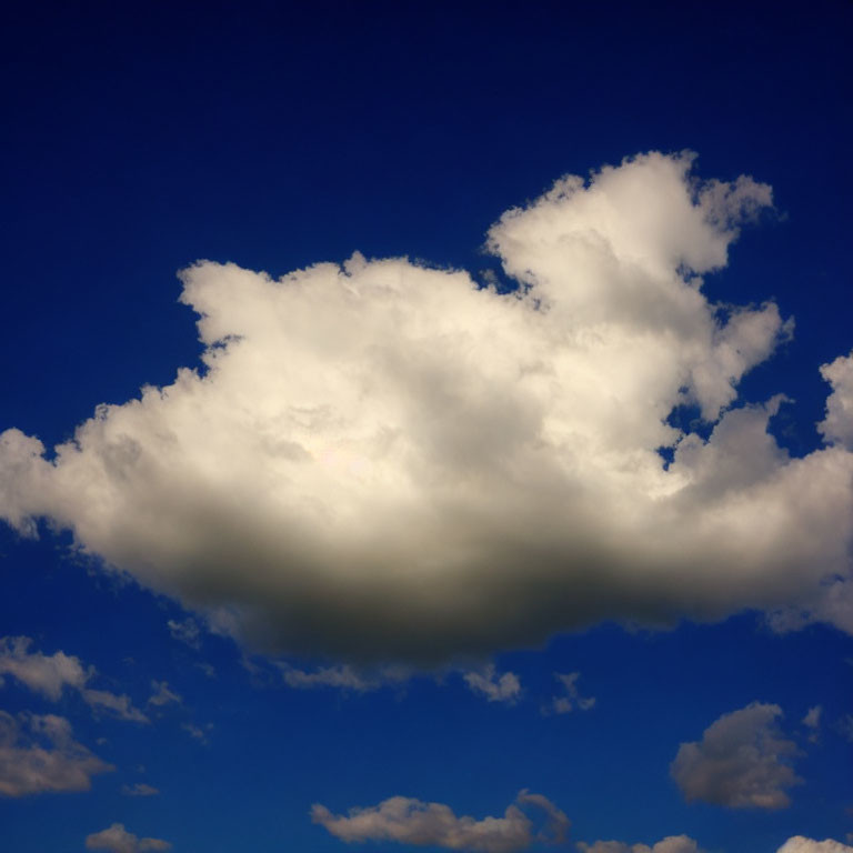 Large Cumulus Cloud in Bright Blue Sky with Sunlight and Other Clouds