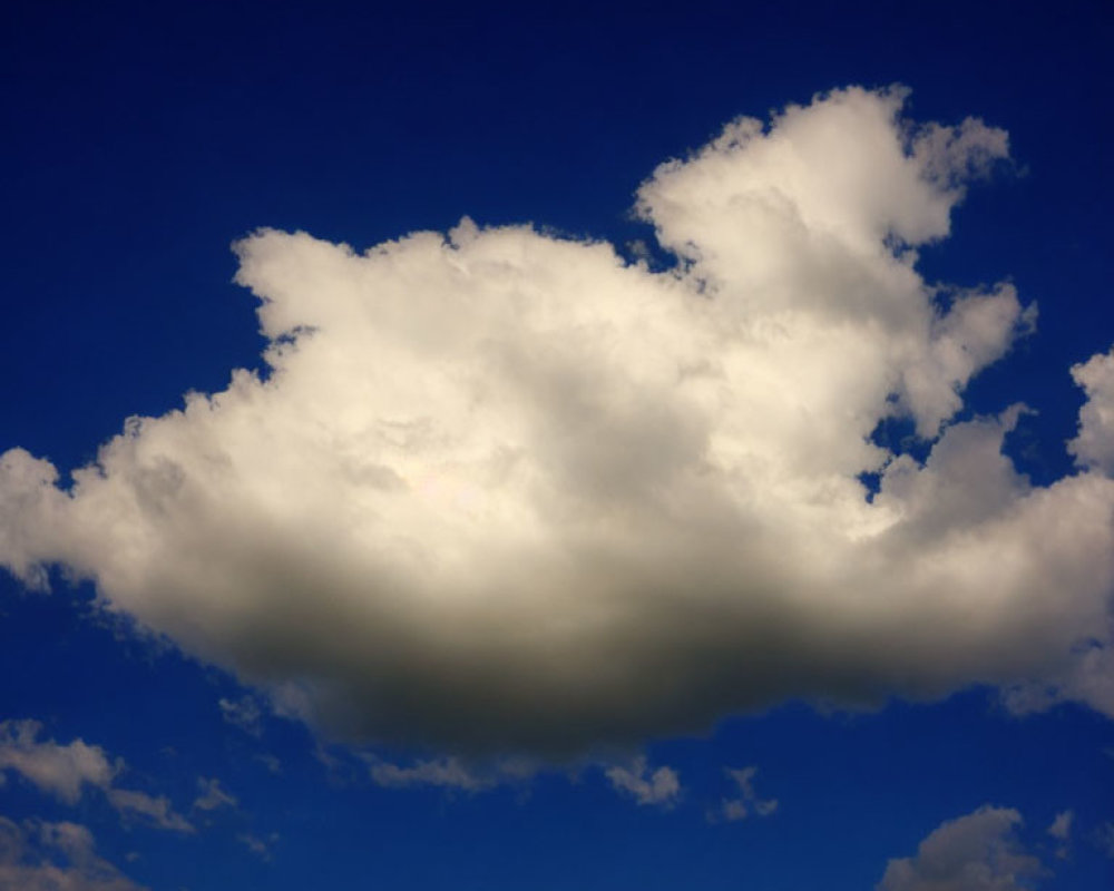 Large Cumulus Cloud in Bright Blue Sky with Sunlight and Other Clouds
