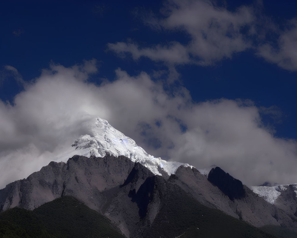 Majestic snow-capped mountain peak above rugged foothills under blue sky