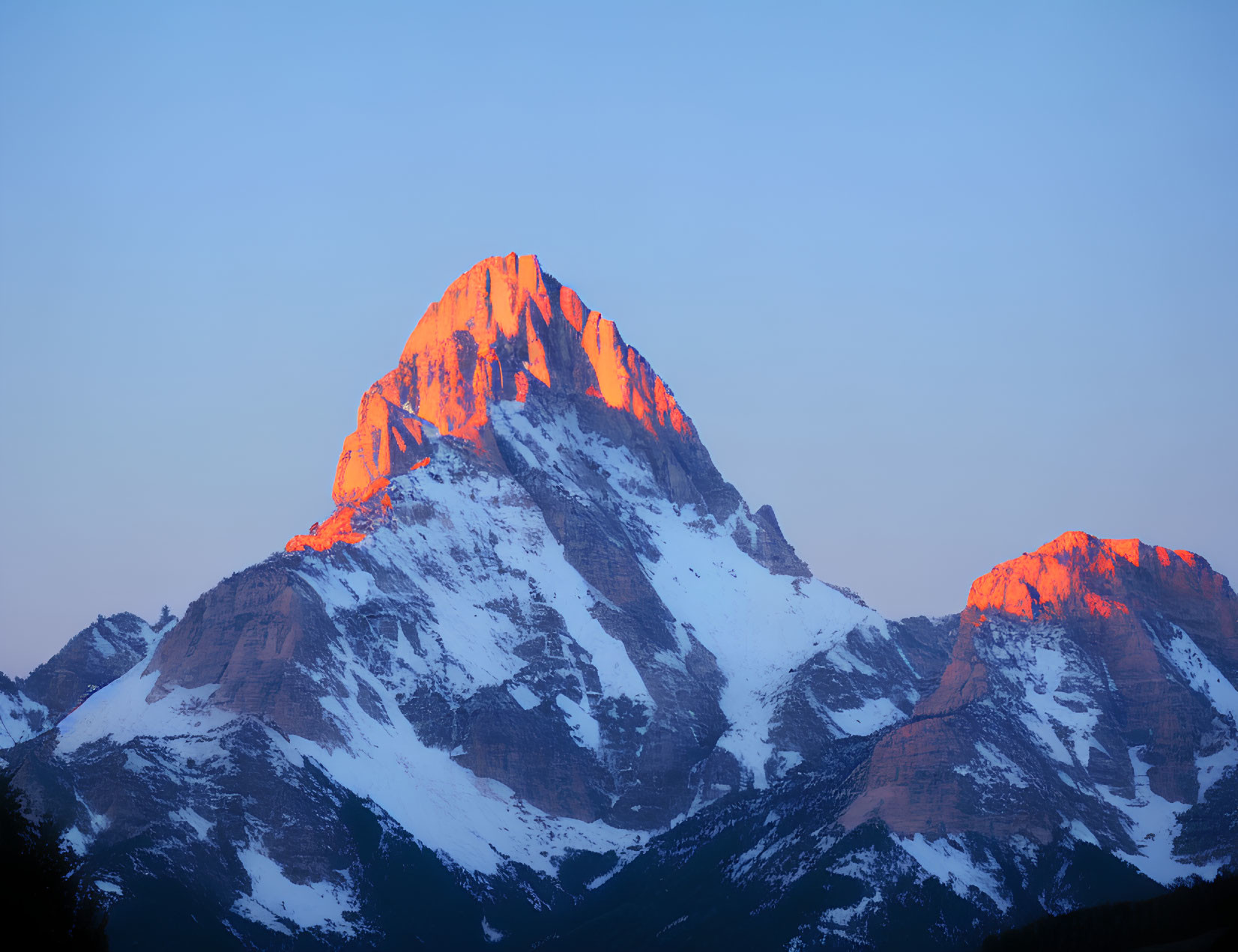 Sunset Alpenglow on Snowy Mountain Peak against Clear Blue Sky