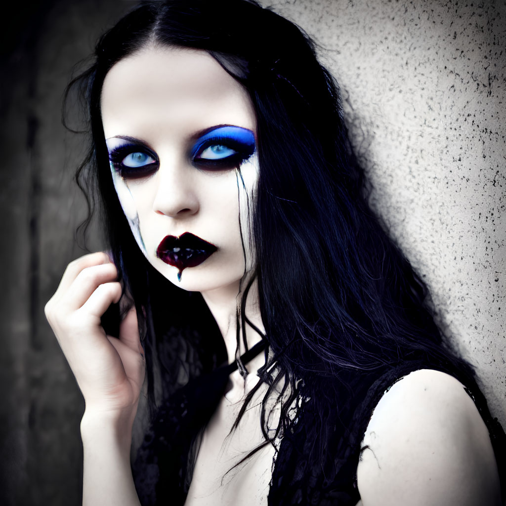 Woman with Dark Makeup and Blue Eyeshadow Against Grey Wall
