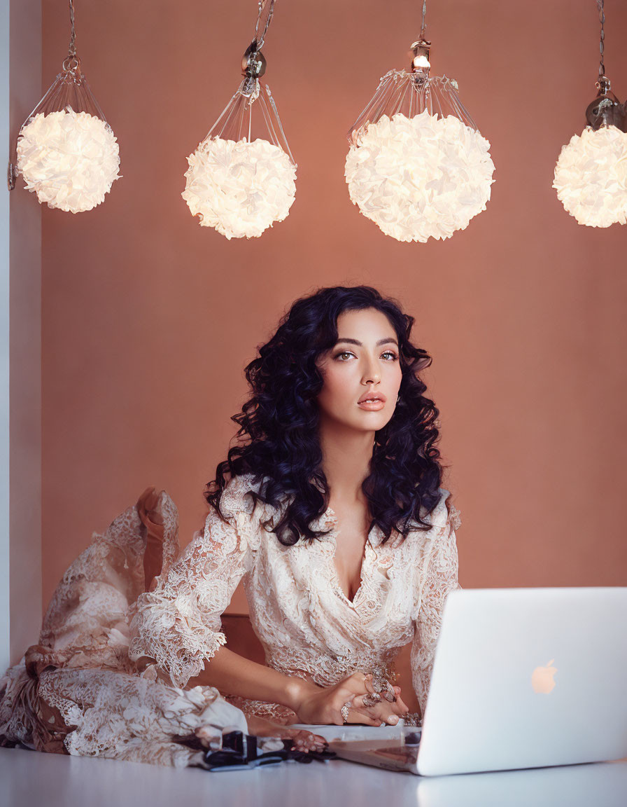 Curly-Haired Woman in Lace Dress at Desk with Laptop and Floral Lights