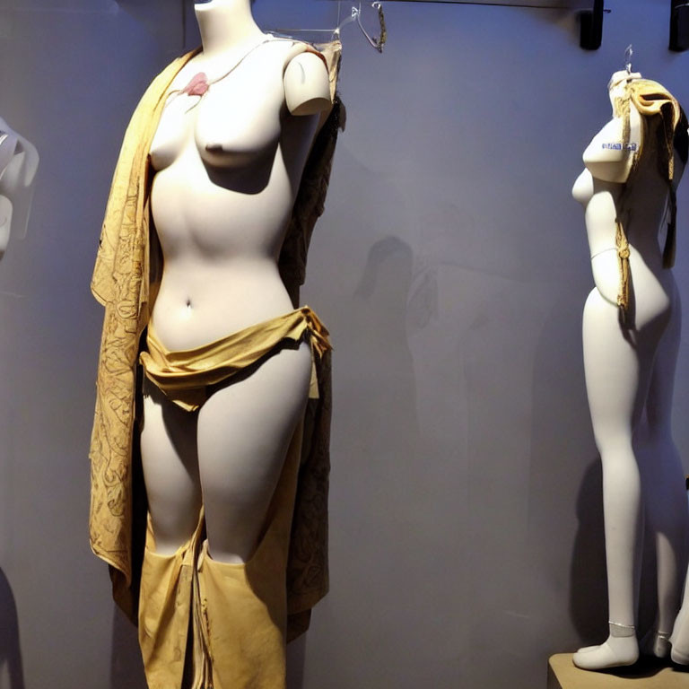 Mannequins in Yellow Toga-Like Outfit & Undressed Garments Displayed in