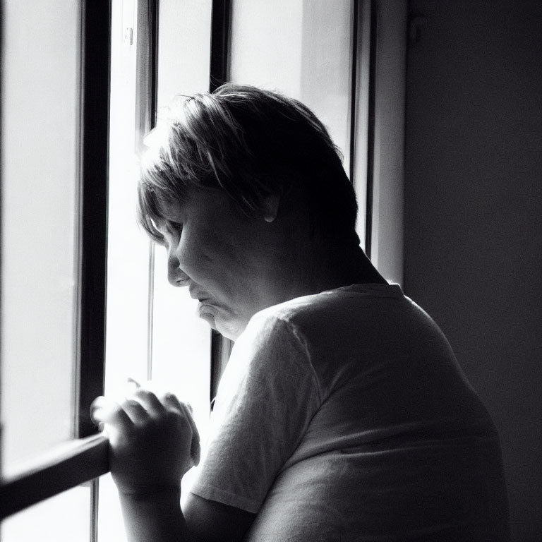 Monochrome portrait of person with short hair gazing out window
