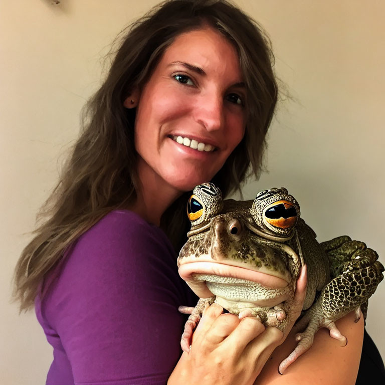 Smiling woman with large frog in purple top