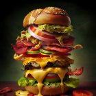 Stacked cheeseburger with multiple beef patties, cheese, lettuce, tomatoes, onions, pickles