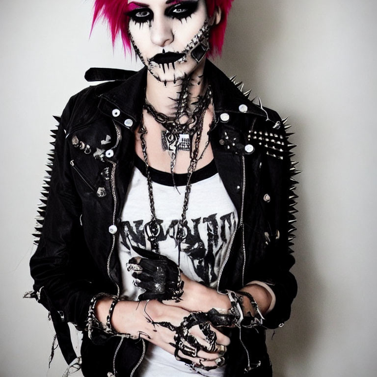 Pink-haired person in punk-style outfit with spikes and heavy makeup.