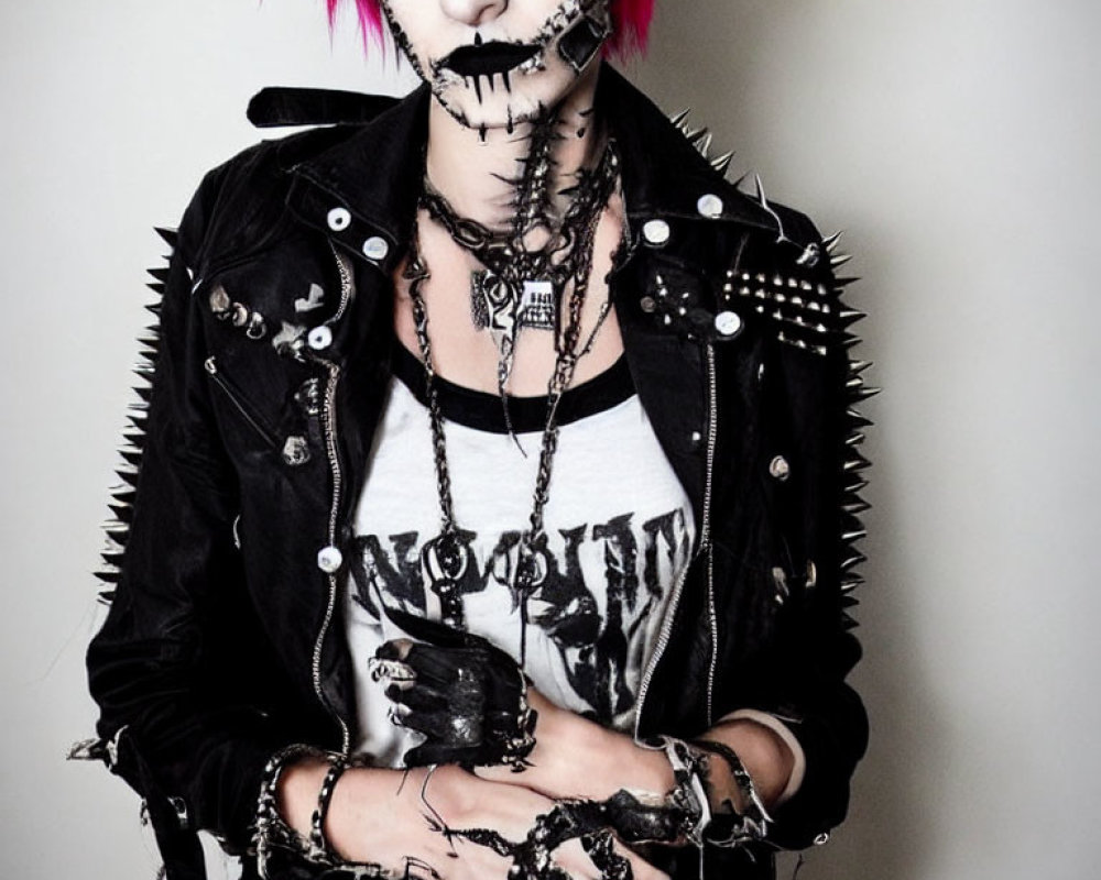 Pink-haired person in punk-style outfit with spikes and heavy makeup.