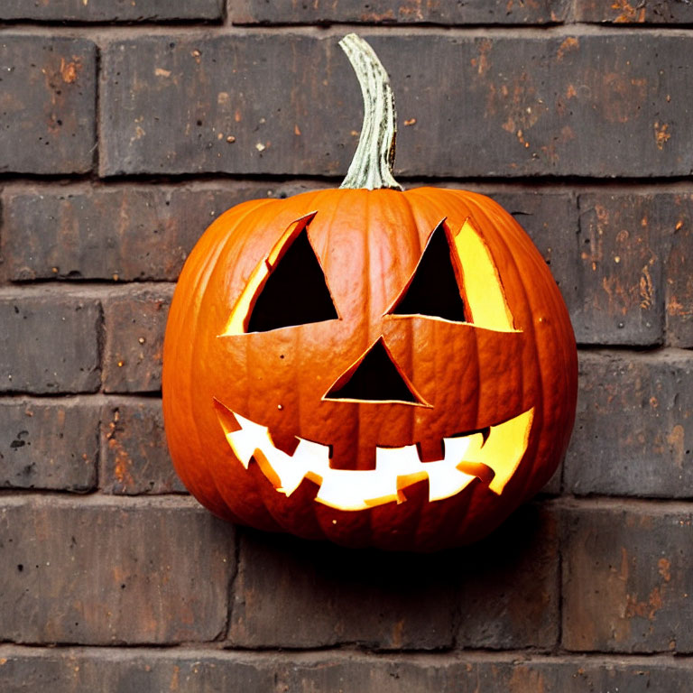 Carved Pumpkin with Jagged Smile and Triangle Eyes on Brick Wall Background