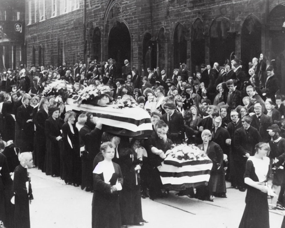 Vintage black and white photo of funeral procession with flower-covered coffins and mourners on street