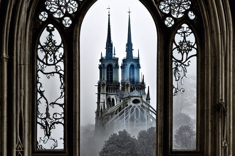Gothic cathedral spires in mist through ornate window frame