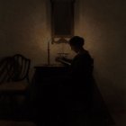 Silhouetted figure reading by candlelight in dark room