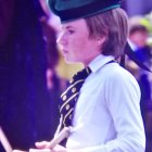Young drum major in traditional uniform playing drums with concentration