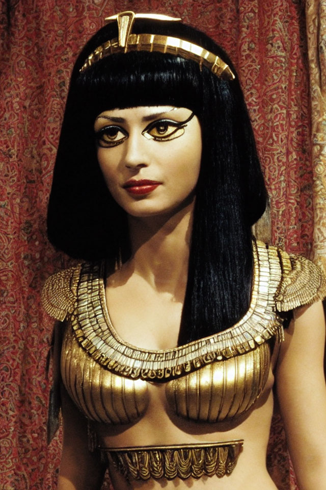 Mannequin in Cleopatra costume with black wig and golden accessories on red backdrop