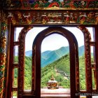 Traditional archway frames vibrant red temple with golden roof amidst green hills and blue sky
