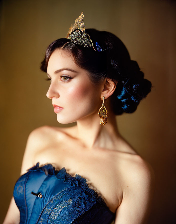 Portrait of woman in blue attire with gold tiara and updo hairstyle