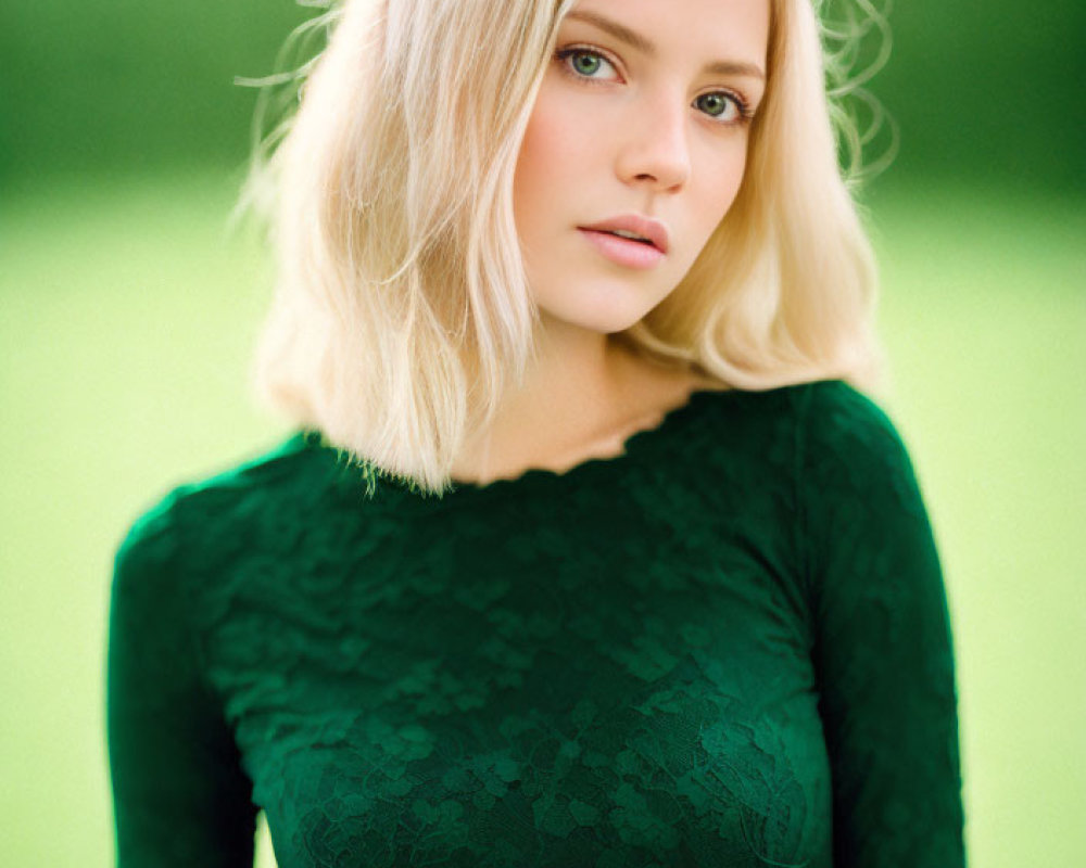 Blonde woman in green lace top against soft green backdrop