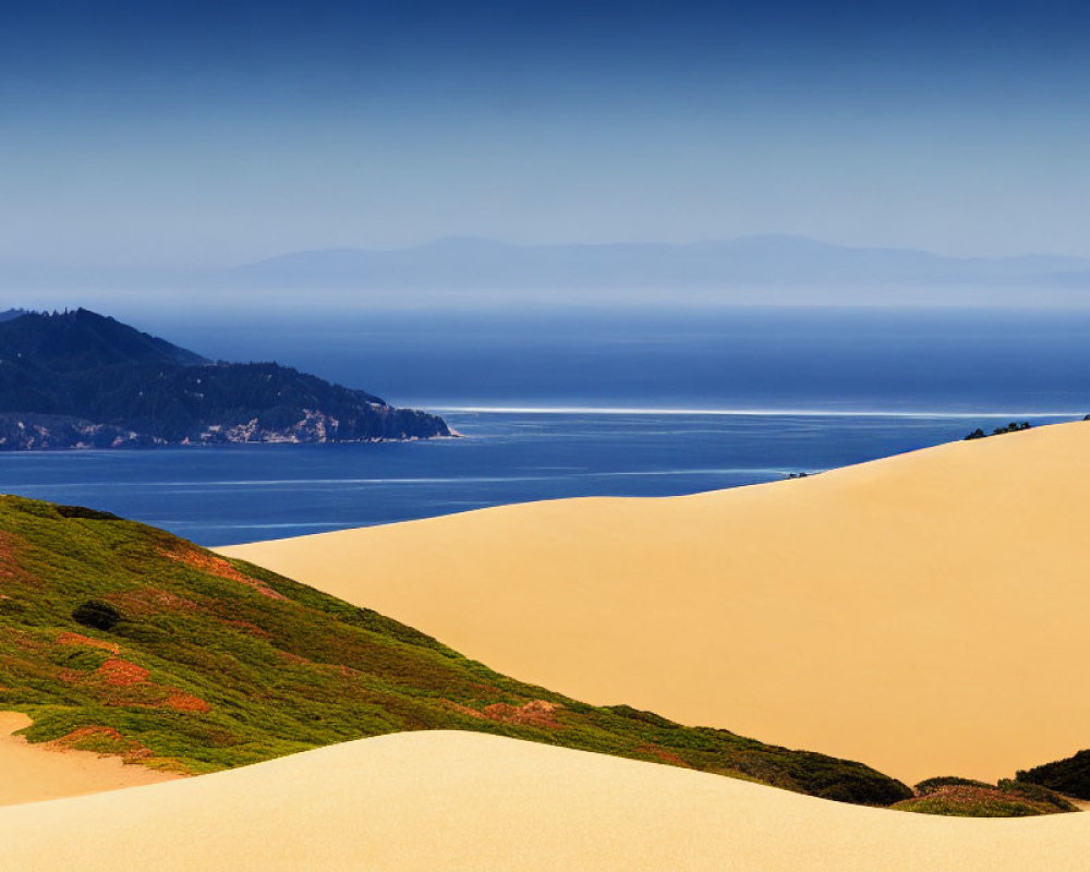 Coastal sand dunes, green vegetation, calm sea, mountains, clear sky