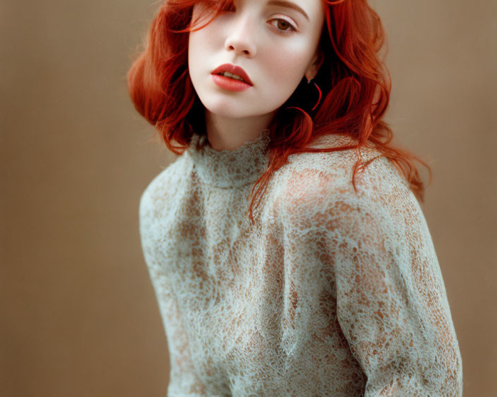 Red-haired woman in lace top against neutral backdrop