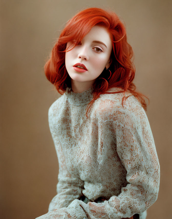 Red-haired woman in lace top against neutral backdrop