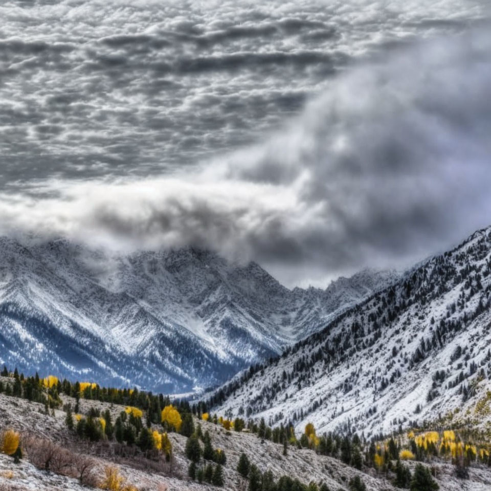 Snow-covered mountains under dramatic cloudy sky with autumn foliage.
