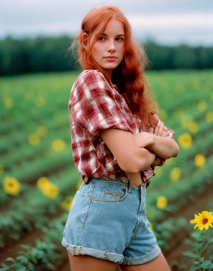 Red-Haired Woman in Plaid Shirt and Denim Shorts Standing in Sunflower Field