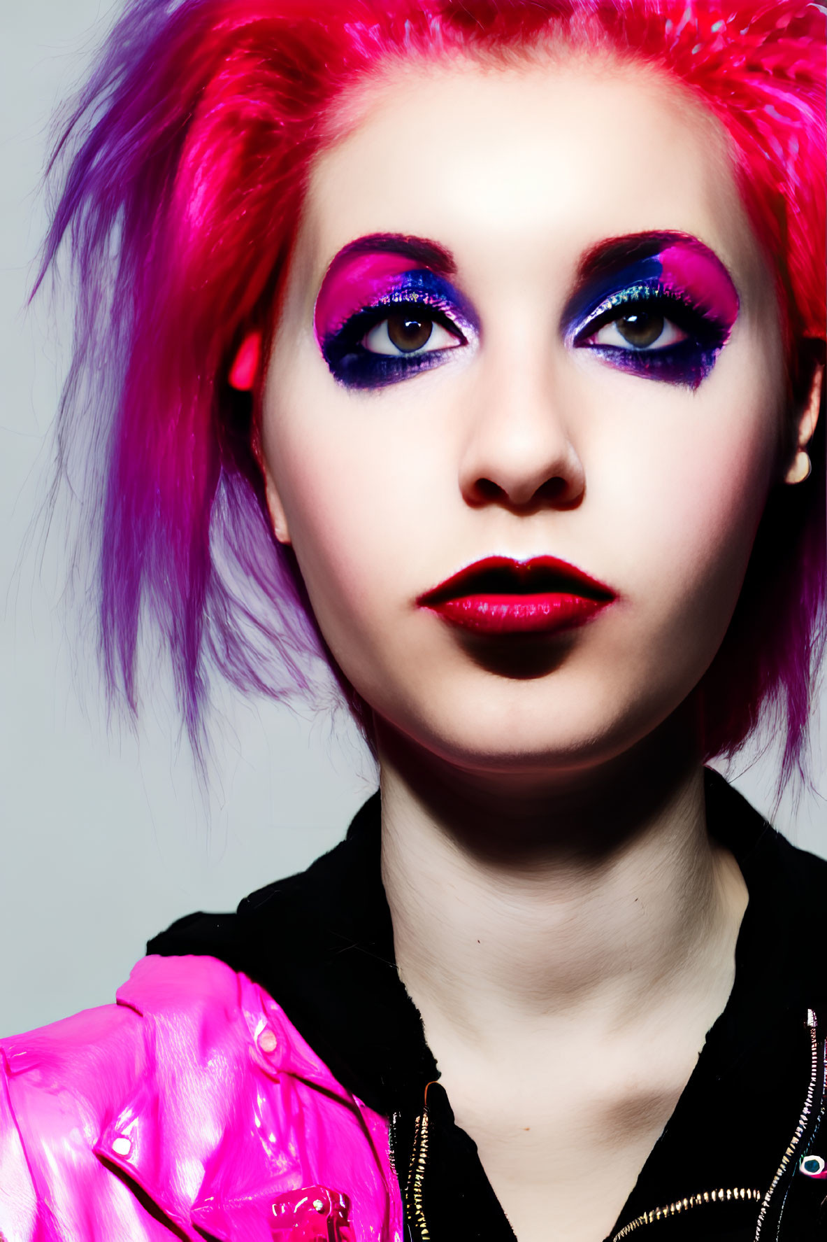Vibrant pink hair woman with bold purple eye makeup in glossy pink jacket