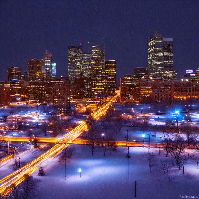 Snow-covered nighttime cityscape with illuminated buildings, streets, and vibrant light trails