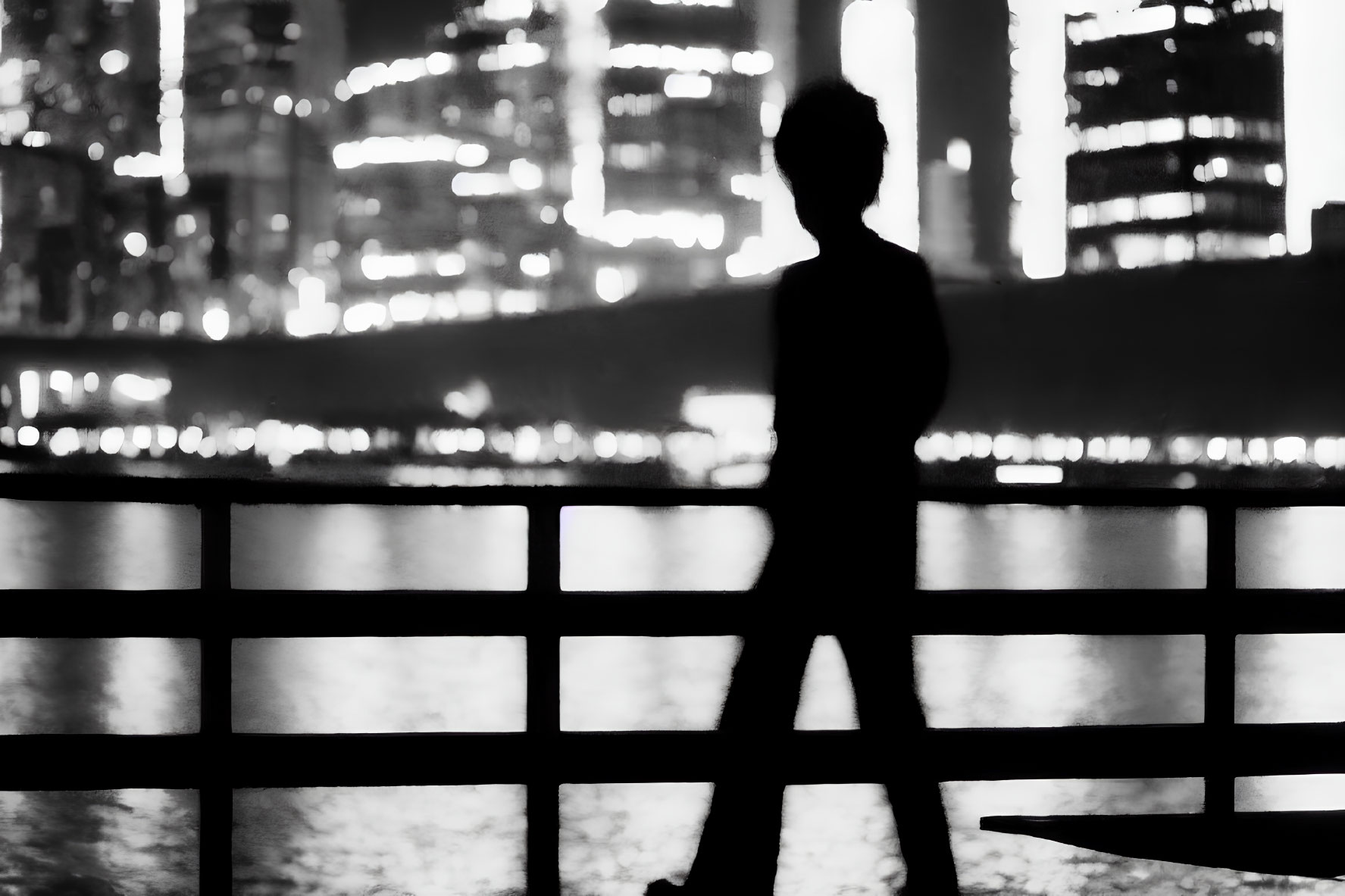 Cityscape silhouette at night with person, water reflections.