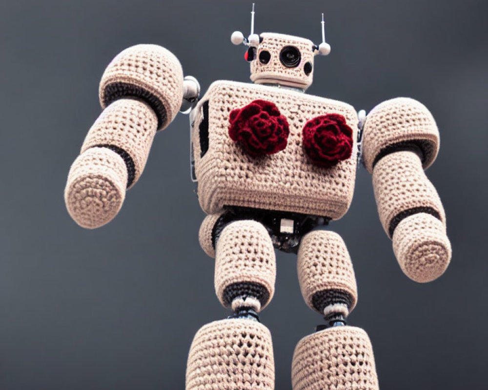 Knitted robot with metallic body and red flowers on chest against grey background