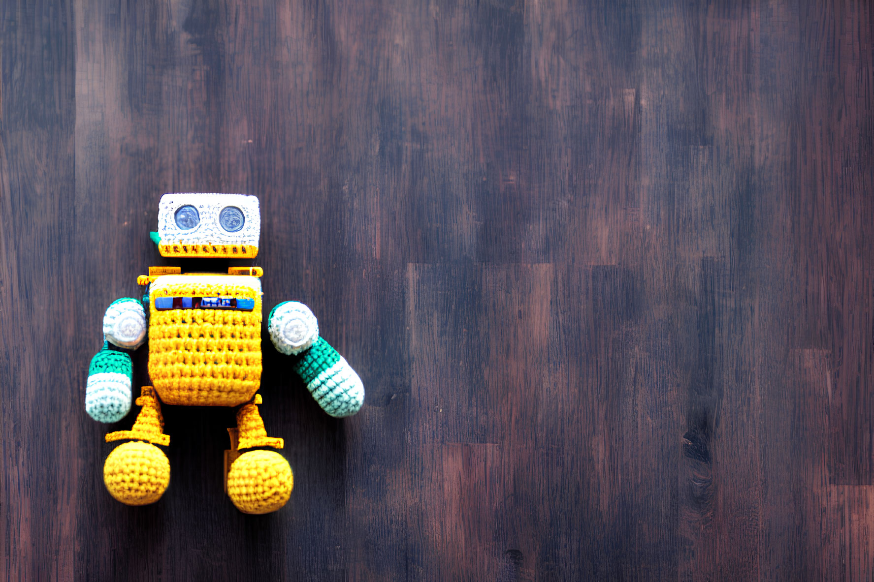 Handmade Crochet Robot Toy in Yellow and Blue on Dark Wooden Background