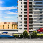 Miniature urban scene with high-rise building, cars, and trees under blue sky