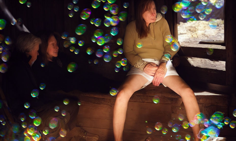 Three Individuals Surrounded by Floating Bubbles in Dimly Lit Wooden Space