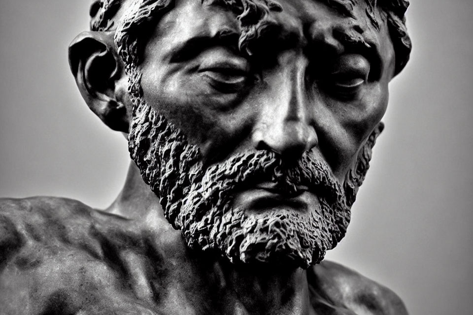Detailed monochrome sculpture of a bearded man with expressive eyes and furrowed brows capturing a p