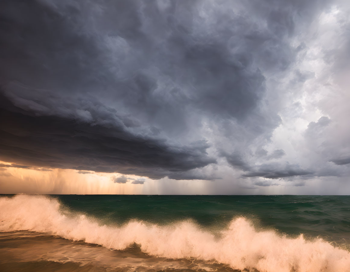 Dark storm clouds over dramatic seascape with sunlight and crashing waves