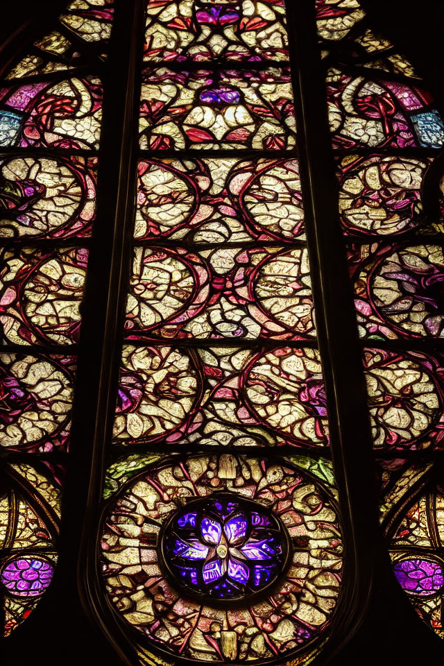 Intricate Gothic stained glass window with vibrant purple, red, and yellow colors