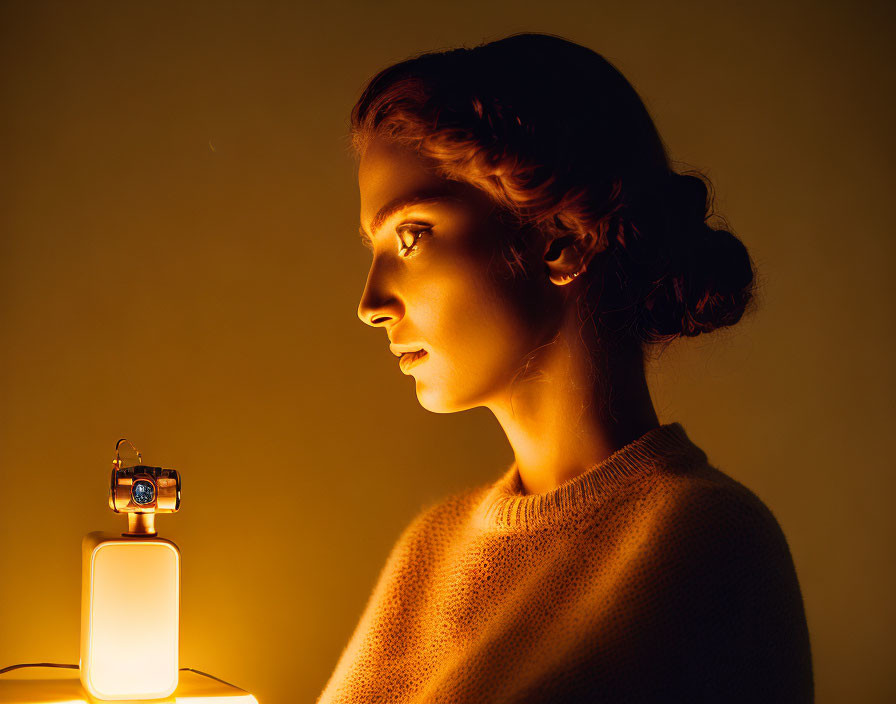 Woman with Braided Hair in Warm Light Beside Lit Lamp