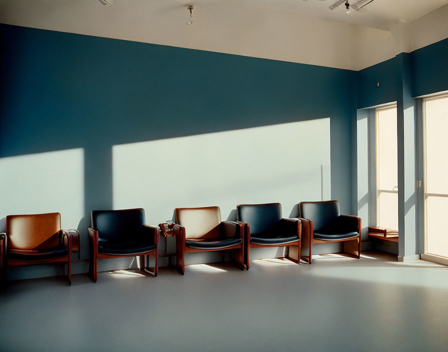 Empty chairs in a sunlit room against blue wall