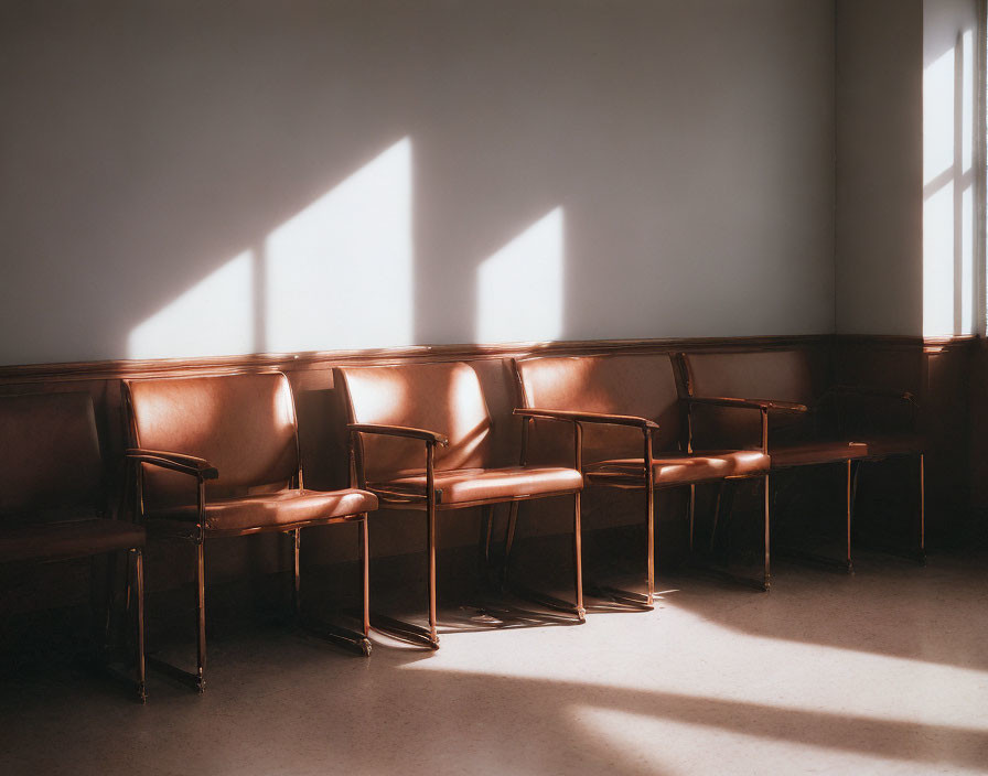 Geometric shadows from sunlight on floor and wall with empty brown chairs