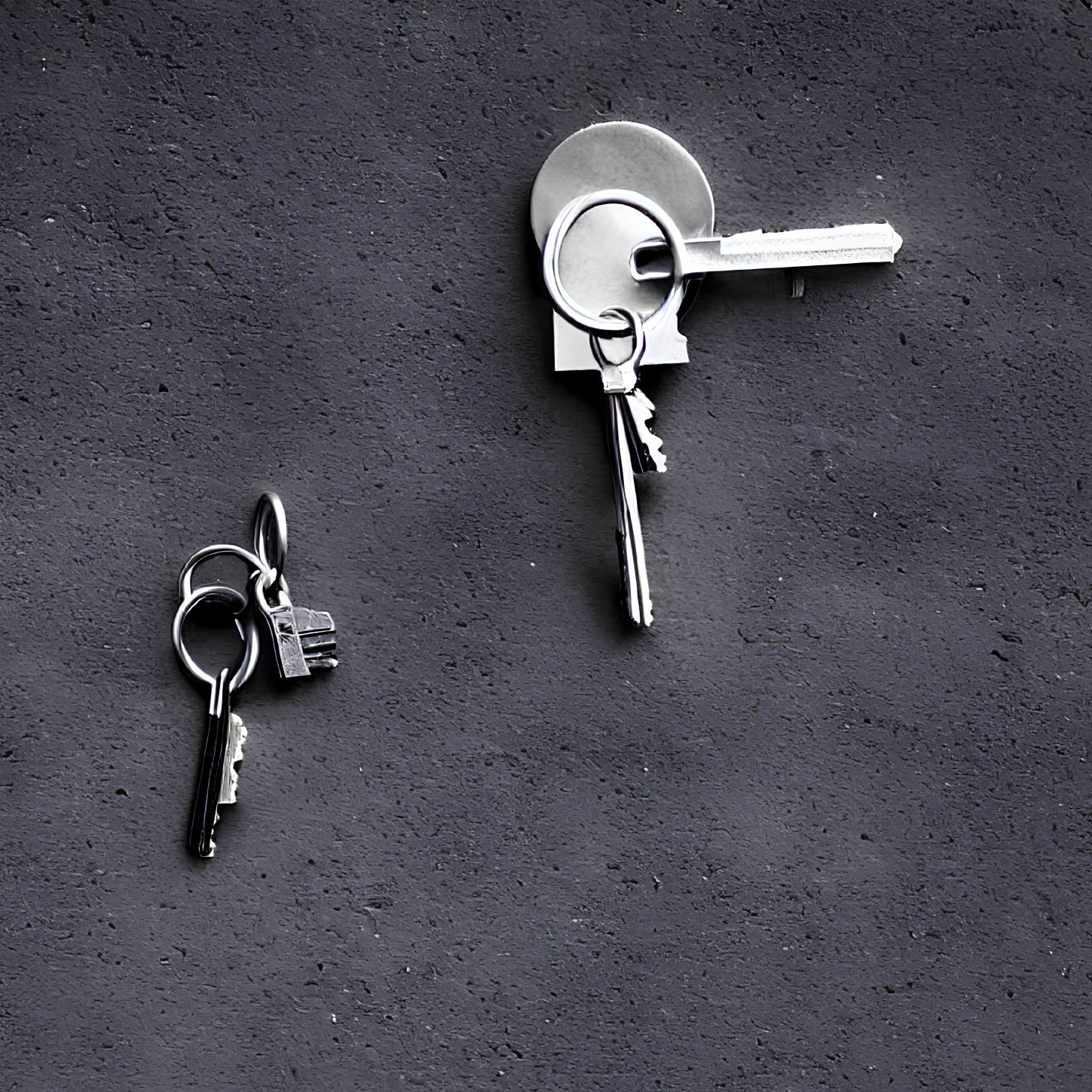 Keys inserted into textured gray wall with another set hanging