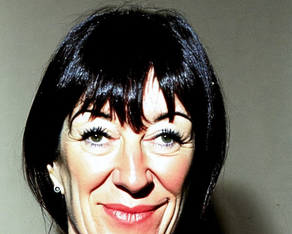 Smiling woman with black hair and bangs portrait.