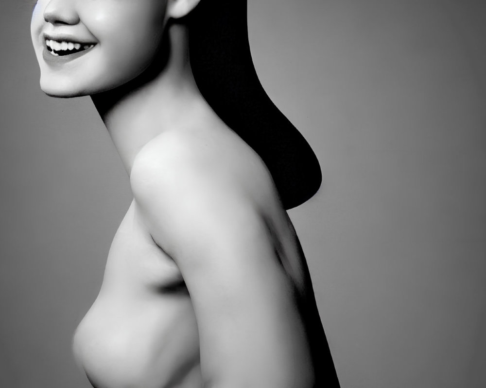 Smiling person's side profile with collarbone and bare shoulders on gray backdrop