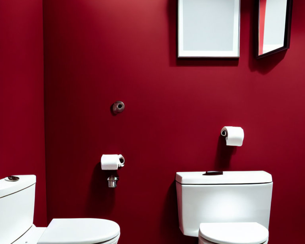 Vivid red wall in modern bathroom with two side-by-side white toilets and empty frames