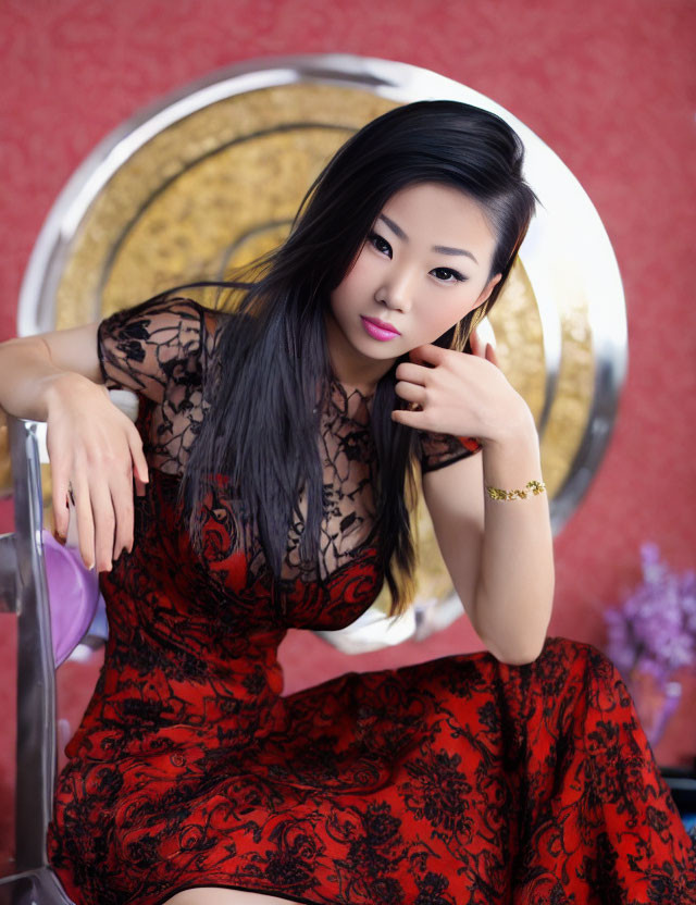 Woman in Red and Black Dress Poses on Metallic Chair with Hand on Chin