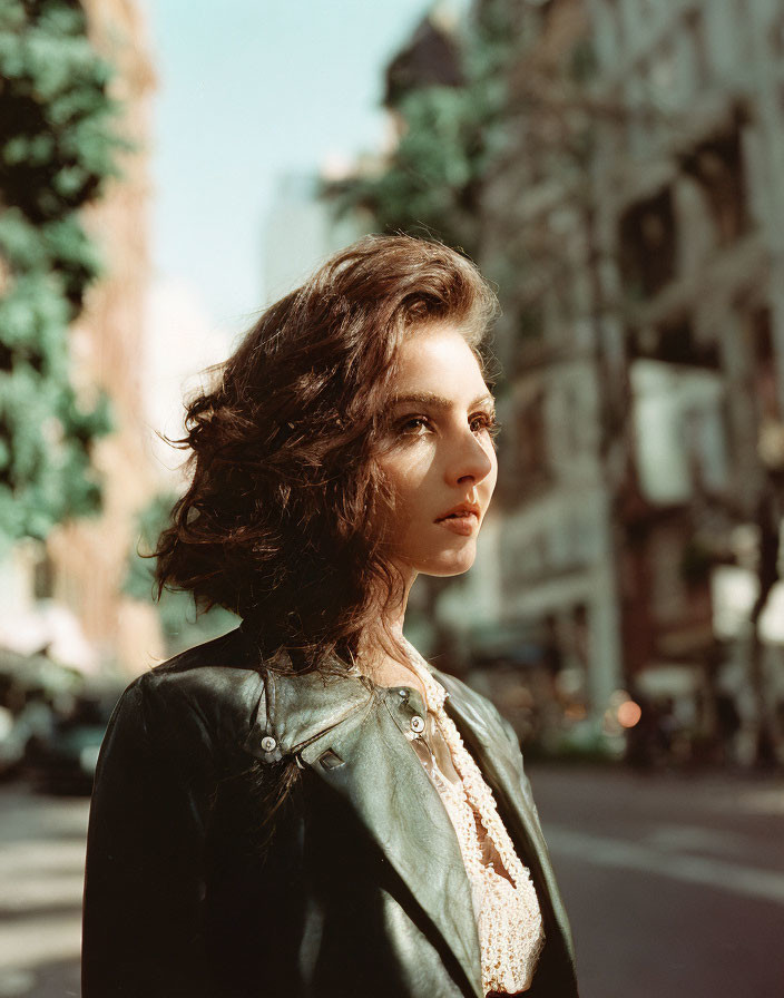 Curly-Haired Woman in Leather Jacket on Sunlit Street