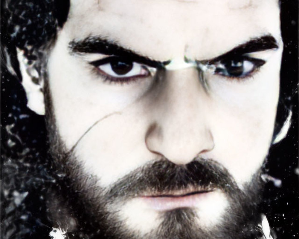 Intense-eyed bearded man with dark hair in snowy setting
